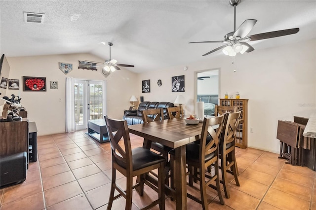 dining room featuring light tile patterned floors, visible vents, vaulted ceiling, a textured ceiling, and french doors