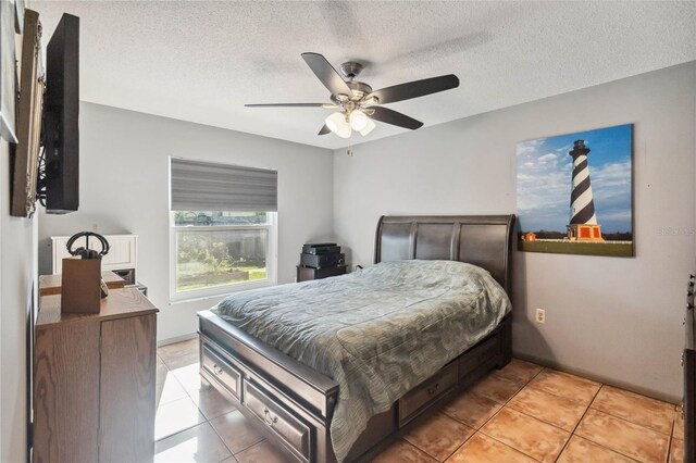 bedroom with ceiling fan, light tile patterned floors, and a textured ceiling