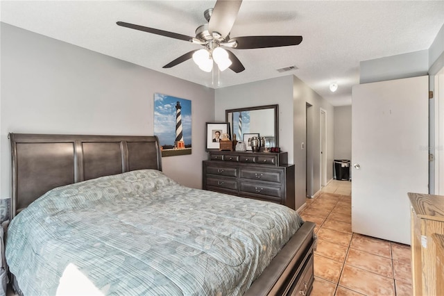 bedroom featuring a ceiling fan, visible vents, a textured ceiling, and light tile patterned floors