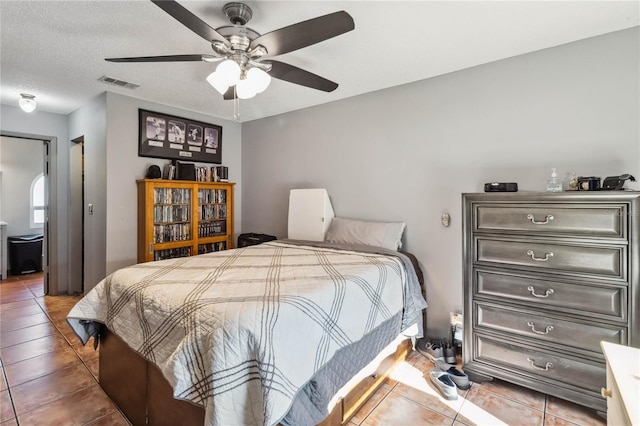 tiled bedroom featuring ceiling fan, visible vents, and a textured ceiling