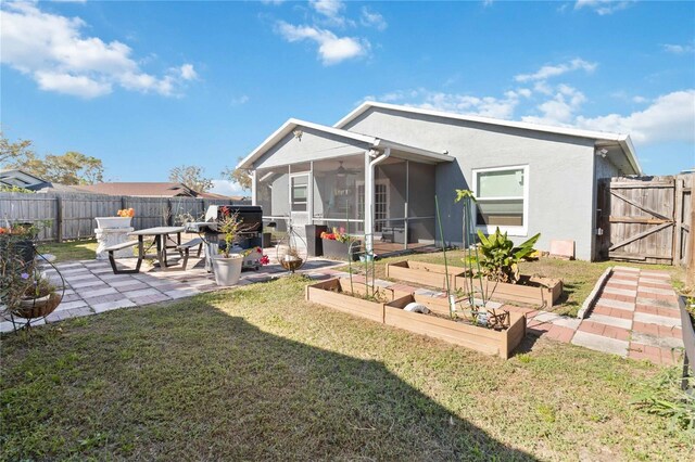 back of property featuring a vegetable garden, a sunroom, a fenced backyard, a yard, and a patio area