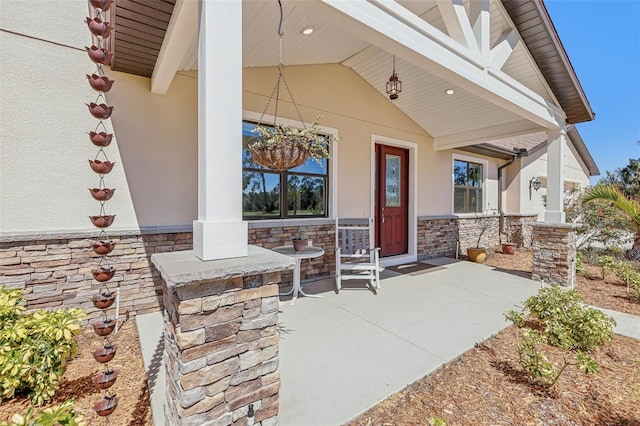 property entrance with stone siding, a porch, and stucco siding