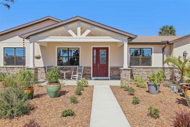 view of front of house featuring a porch, stone siding, and stucco siding