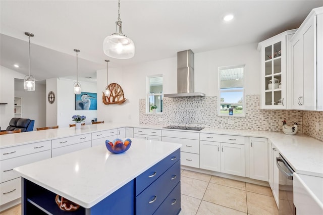 kitchen with glass insert cabinets, wall chimney range hood, blue cabinets, dishwasher, and black electric cooktop