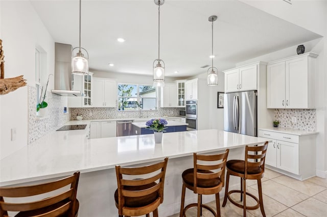 kitchen with decorative backsplash, appliances with stainless steel finishes, glass insert cabinets, a peninsula, and wall chimney exhaust hood