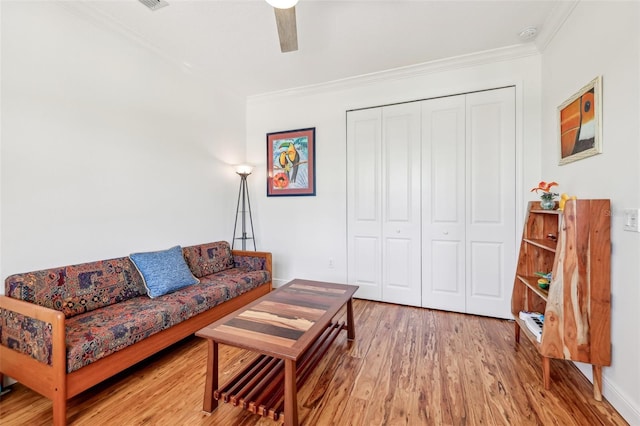 living area with ceiling fan, crown molding, and wood finished floors