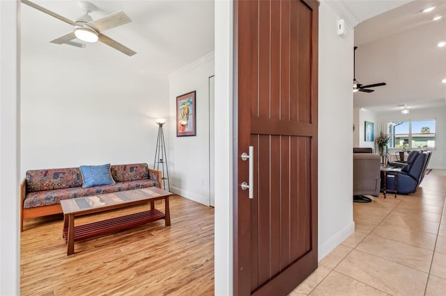 living area with light tile patterned floors, baseboards, a ceiling fan, and crown molding