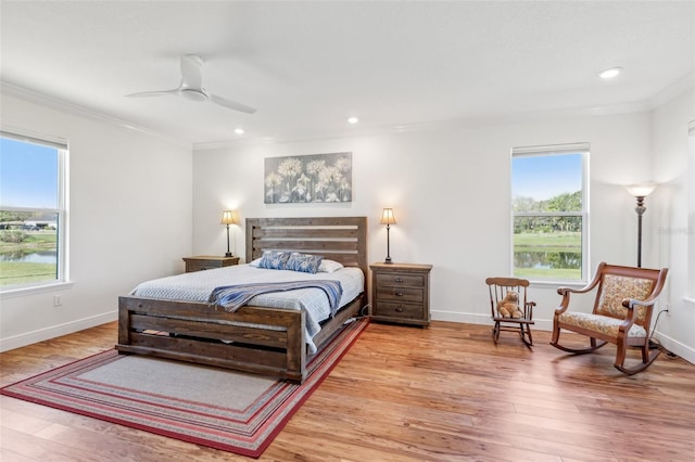 bedroom featuring ornamental molding, multiple windows, and light wood-style floors