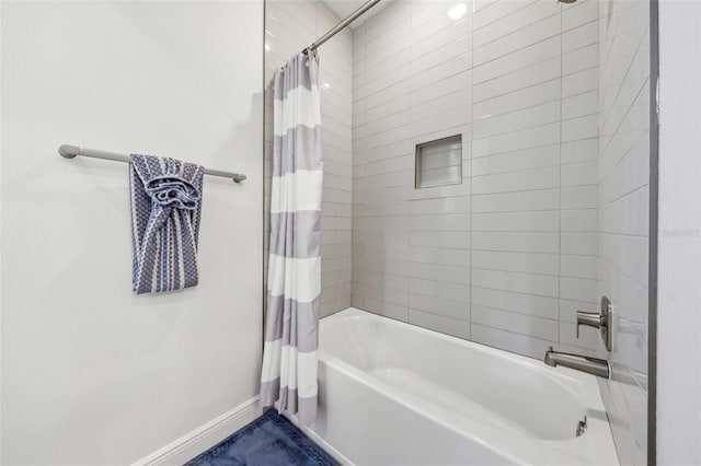 bathroom featuring shower / tub combo and baseboards