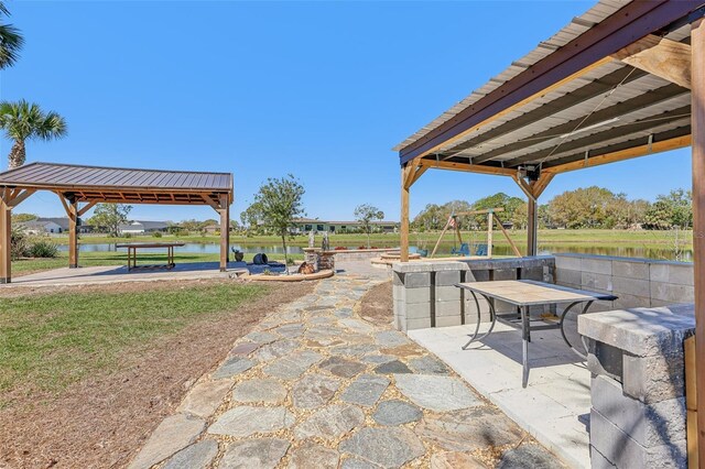 surrounding community featuring a gazebo, outdoor dining area, a patio area, and a water view