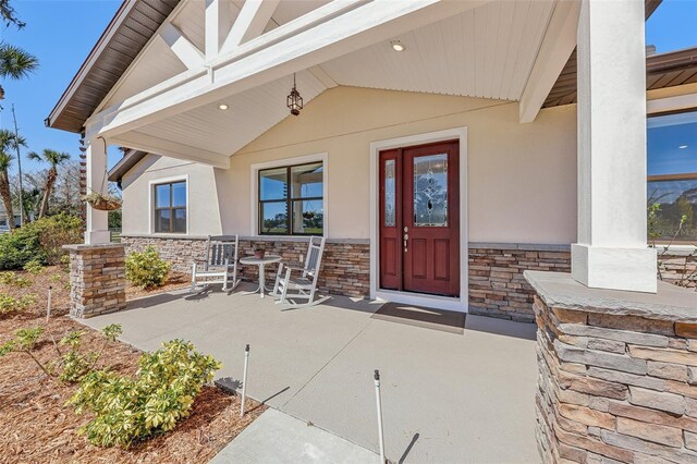 3607 Hidden River Ln, Tavares, FL 32778 - doorway to property featuring stone siding, stucco siding, and covered porch