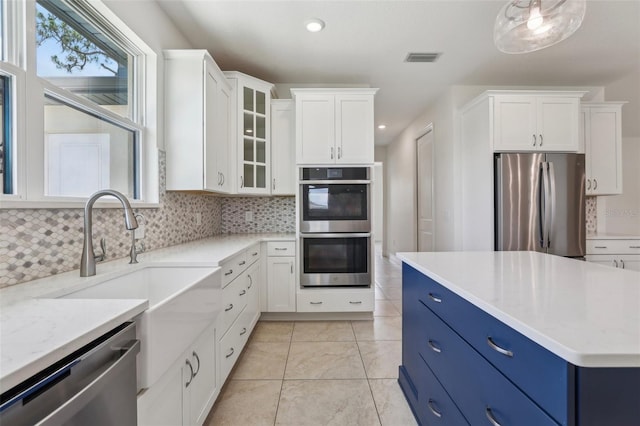 3607 Hidden River Ln, Tavares, FL 32778 - kitchen with appliances with stainless steel finishes, blue cabinetry, plenty of natural light, white cabinets, and recessed lighting