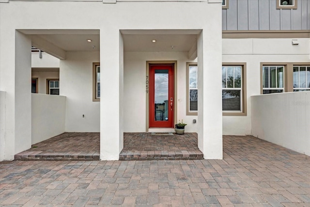 property entrance with board and batten siding and stucco siding