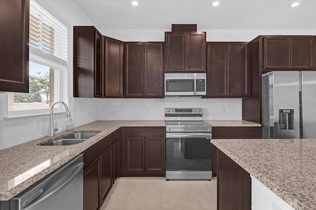 kitchen featuring appliances with stainless steel finishes, light tile patterned floors, a sink, and tasteful backsplash