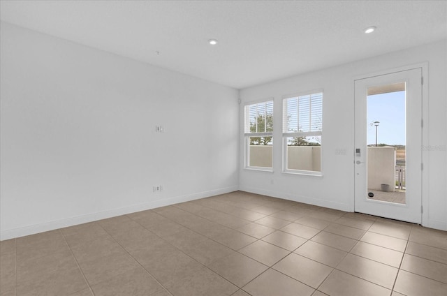 empty room featuring light tile patterned floors, baseboards, and recessed lighting