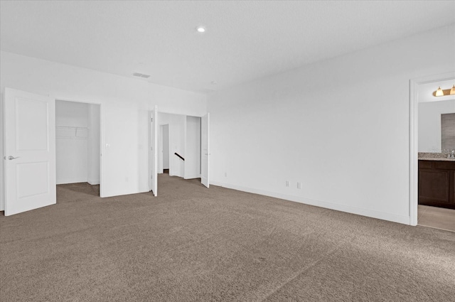 unfurnished bedroom with carpet floors, visible vents, baseboards, and ensuite bathroom