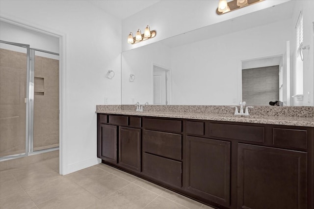 full bathroom with double vanity, a stall shower, a sink, and tile patterned floors