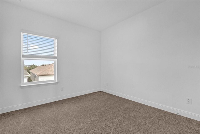 carpeted empty room featuring baseboards