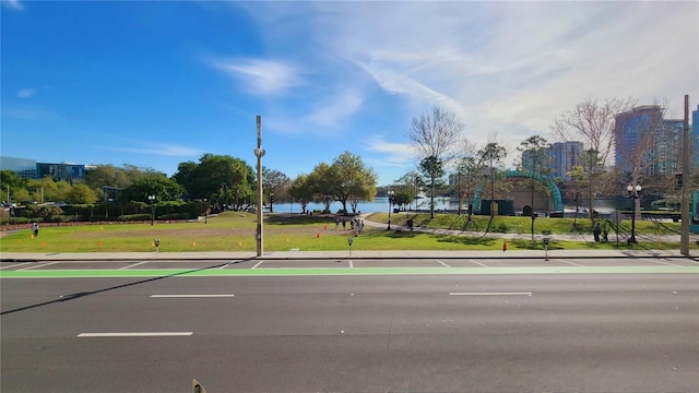 view of road featuring curbs, a water view, and sidewalks