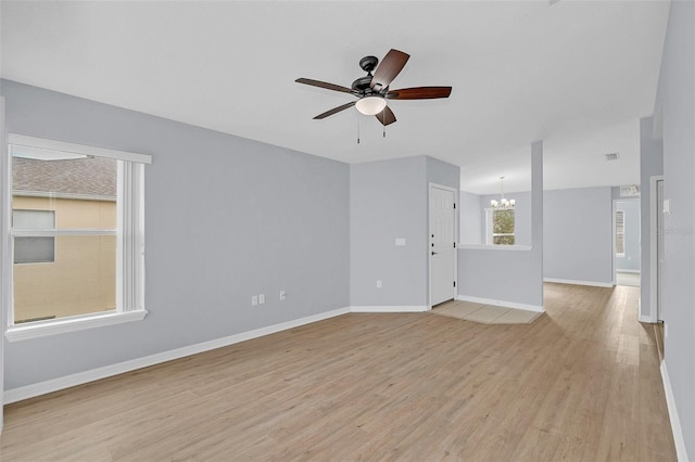 unfurnished living room featuring ceiling fan with notable chandelier, light wood-style flooring, and baseboards