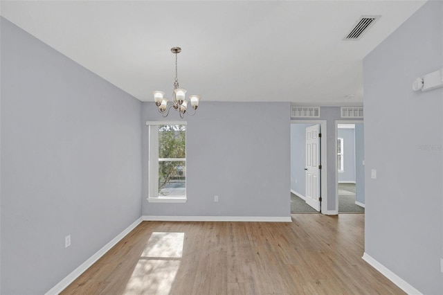 spare room featuring baseboards, visible vents, and wood finished floors