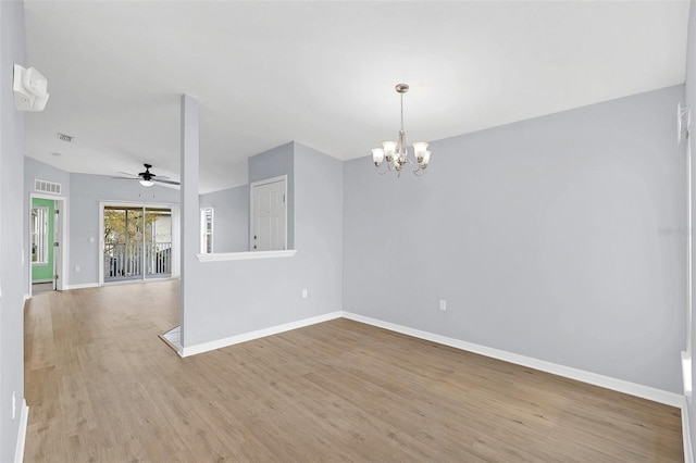 spare room with ceiling fan with notable chandelier, wood finished floors, visible vents, and baseboards