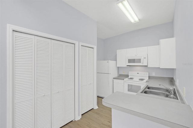 kitchen featuring white appliances, light wood-style flooring, light countertops, white cabinetry, and a sink