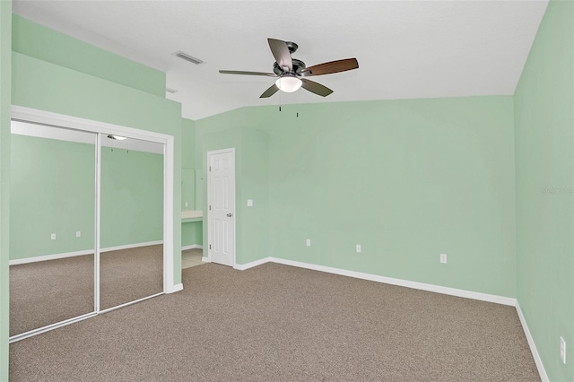 unfurnished bedroom featuring baseboards, visible vents, vaulted ceiling, carpet floors, and a closet