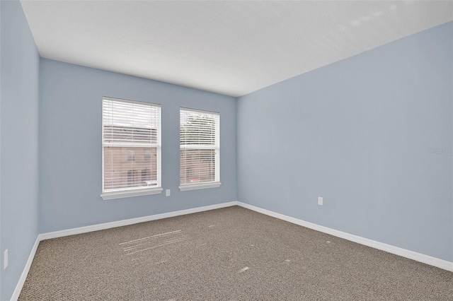 empty room featuring carpet floors and baseboards