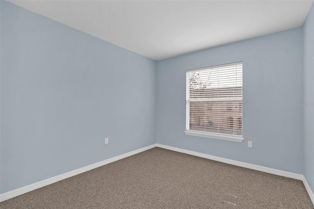 unfurnished room with dark carpet and baseboards