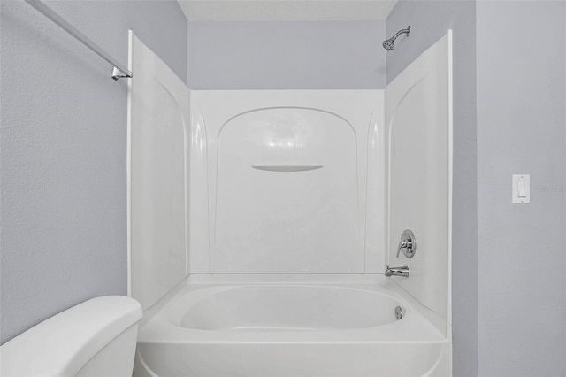 full bath featuring  shower combination, toilet, and a textured wall