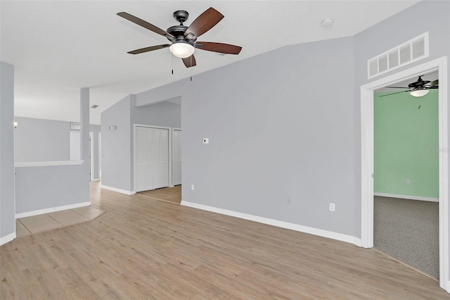 spare room featuring lofted ceiling, visible vents, light wood-style flooring, and baseboards