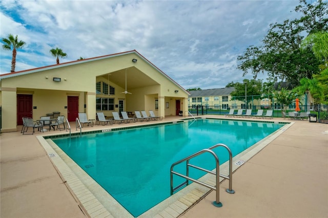 community pool with a patio area and fence