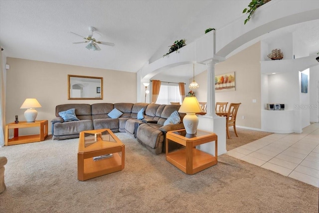 carpeted living area featuring decorative columns, arched walkways, ceiling fan, tile patterned flooring, and vaulted ceiling