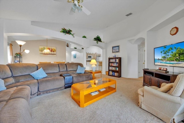 living room with light colored carpet, arched walkways, visible vents, and lofted ceiling