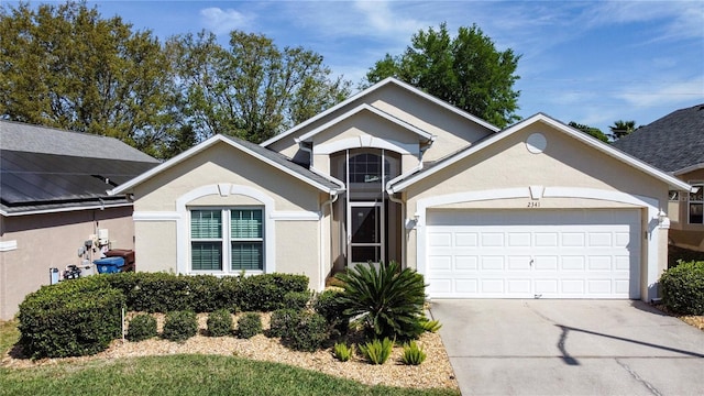 view of front facade with stucco siding, an attached garage, and driveway