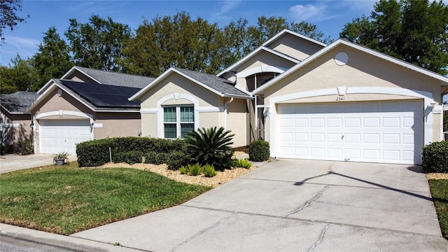 ranch-style house with stucco siding, driveway, an attached garage, and a front lawn