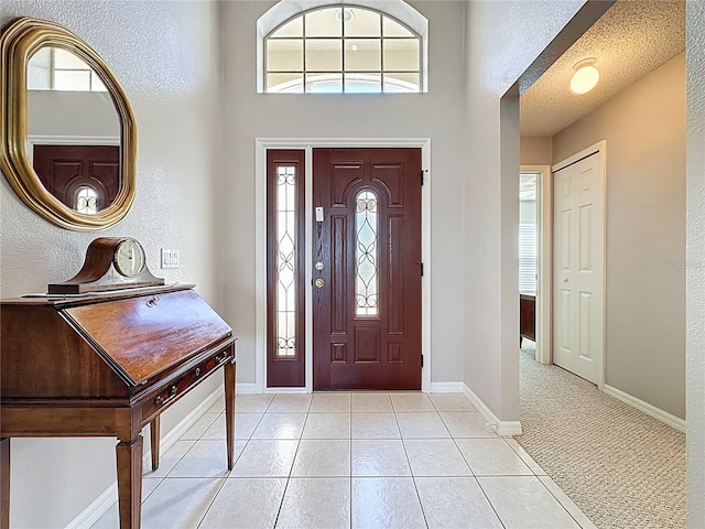 foyer entrance with light tile patterned floors, baseboards, and a textured ceiling