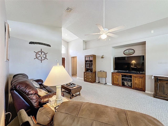 living room featuring visible vents, a ceiling fan, a textured ceiling, baseboards, and light colored carpet