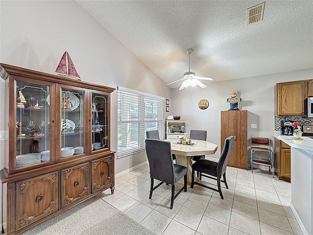 dining area featuring light tile patterned floors, visible vents, ceiling fan, and vaulted ceiling