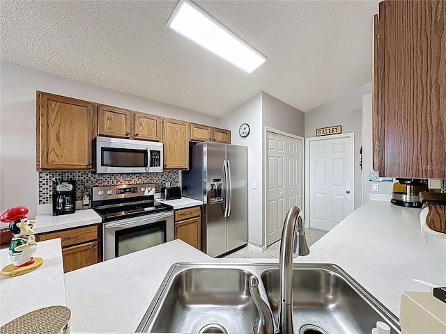 kitchen featuring light countertops, vaulted ceiling, brown cabinets, stainless steel appliances, and a sink