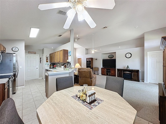 dining space with a ceiling fan, visible vents, lofted ceiling, light tile patterned flooring, and light carpet