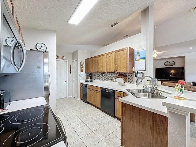 kitchen featuring light countertops, brown cabinets, appliances with stainless steel finishes, a peninsula, and a sink