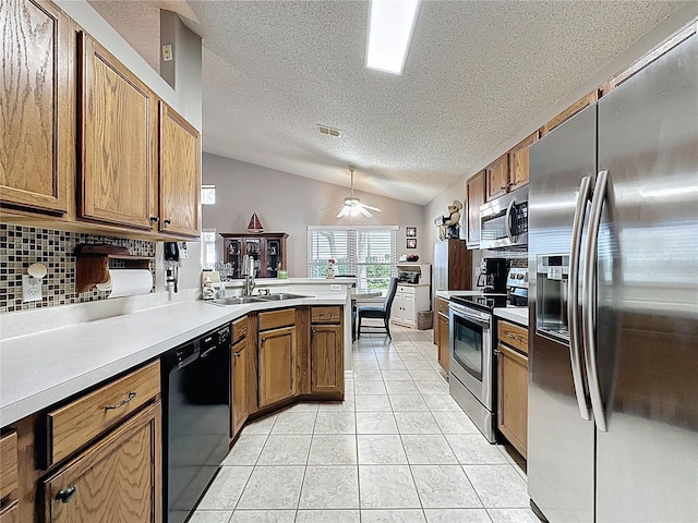 kitchen featuring visible vents, tasteful backsplash, stainless steel appliances, a peninsula, and brown cabinetry