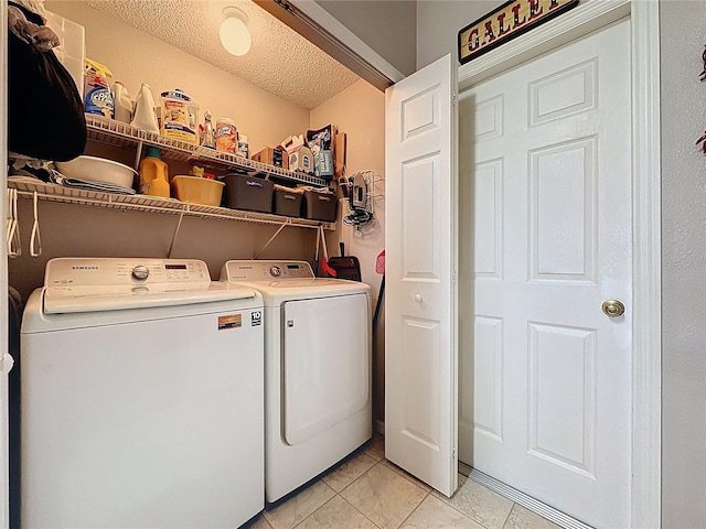 laundry room featuring washing machine and clothes dryer, laundry area, a textured ceiling, and light tile patterned floors