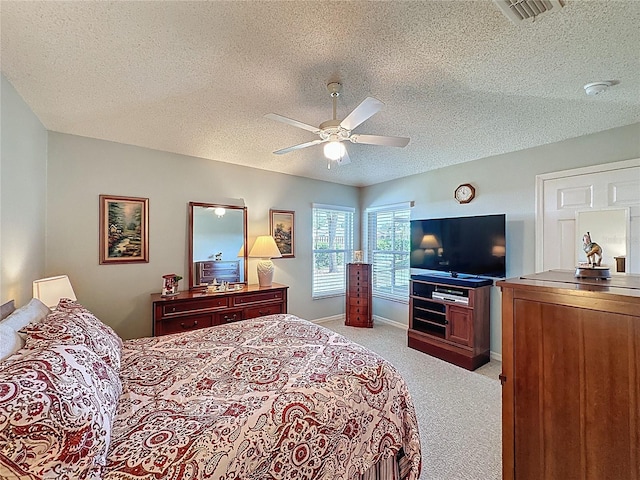 bedroom with a ceiling fan, baseboards, visible vents, a textured ceiling, and light carpet