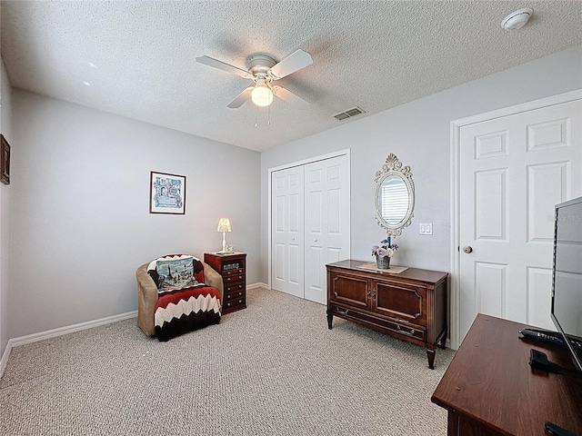 sitting room featuring visible vents, a textured ceiling, carpet, and a ceiling fan