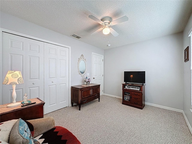 living area featuring visible vents, a ceiling fan, a textured ceiling, baseboards, and light colored carpet