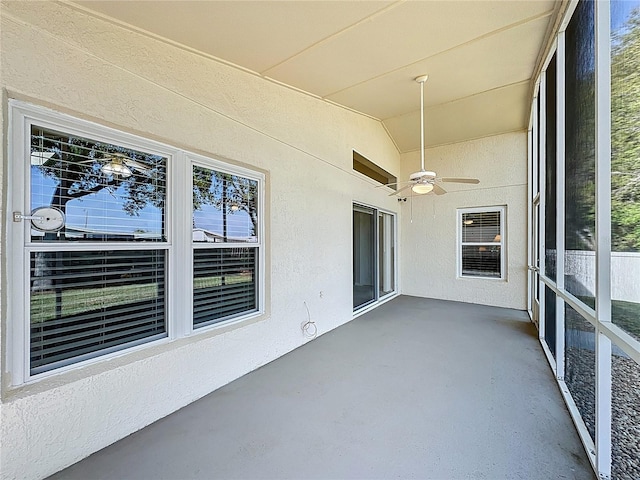 unfurnished sunroom with a ceiling fan and vaulted ceiling