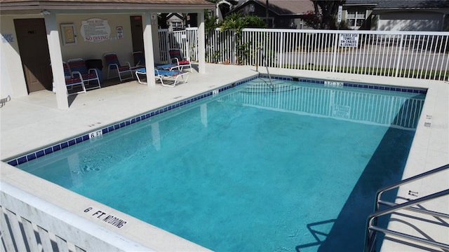 community pool with a patio area and fence